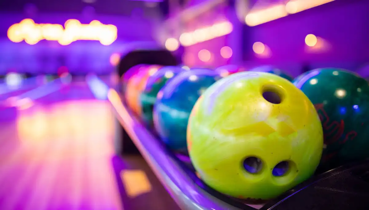 Colourful bowling balls lined up under neon lights at a bowling alley