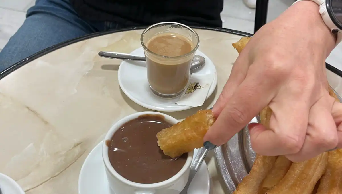 Dipping a churro into thick hot chocolate with a coffee at Casa Aranda in Malaga