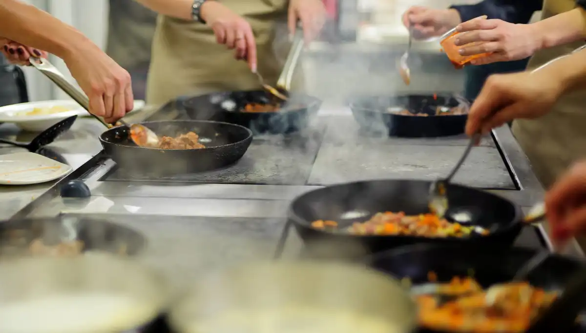 Hands cooking in pans at a Spanish cooking class in Malaga