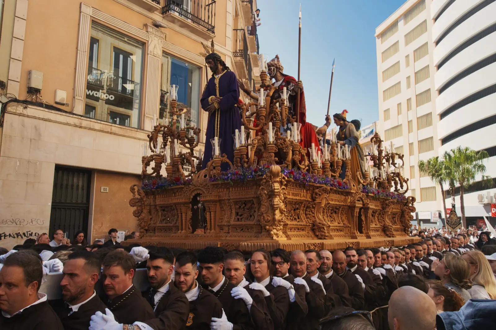 Costaleros carrying an ornate Semana Santa float through the streets of Málaga