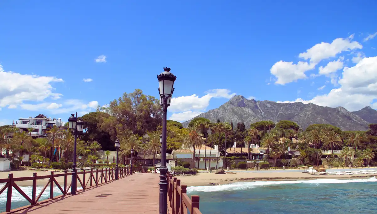 Wooden promenade along Marbella beach with Sierra Blanca mountains in the background