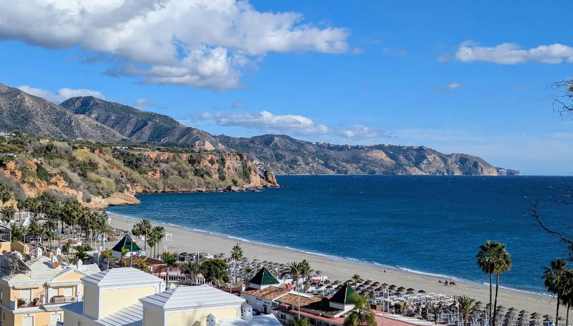 Wide golden sandy beach at Playa Burriana, Nerja, with cliffs in the background