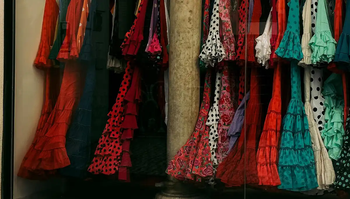 Colourful flamenco dresses hanging in a shop window in Seville