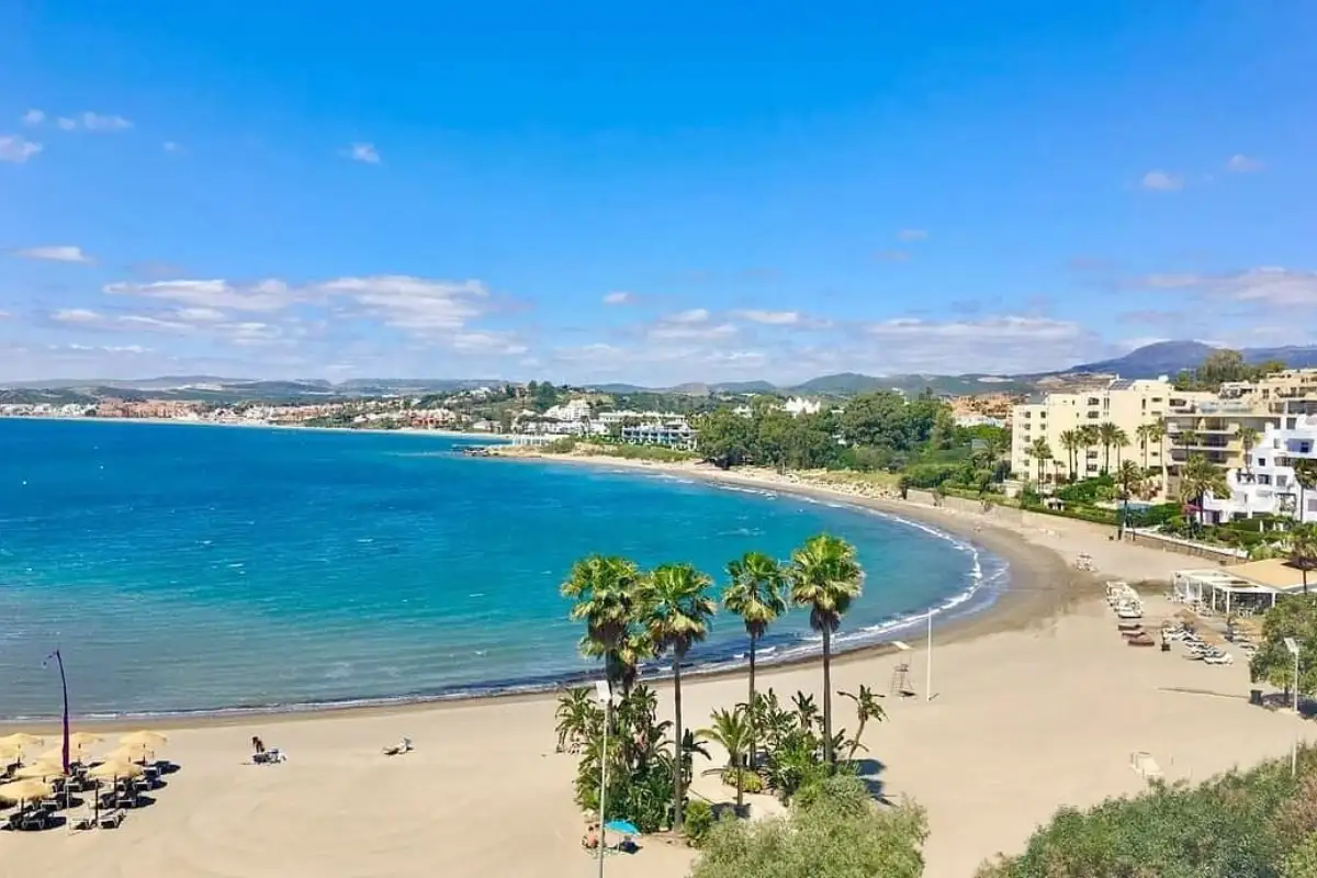 A curving coastline lined with apartment buildings, golden sand, and ocean in Estepona.