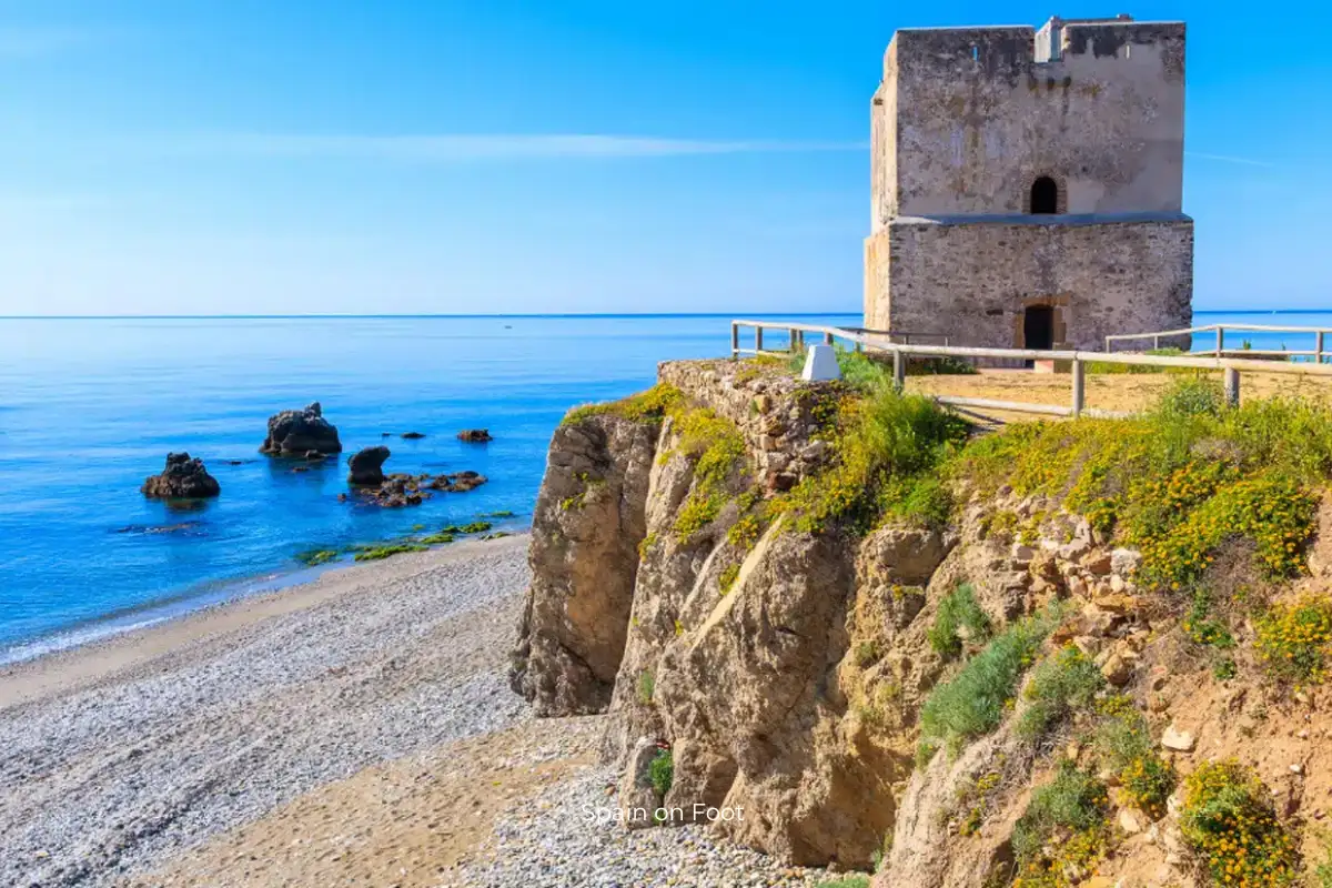 An old castle on a cliff on the blue ocean, framed by a blue skyline at Playa de Galera.