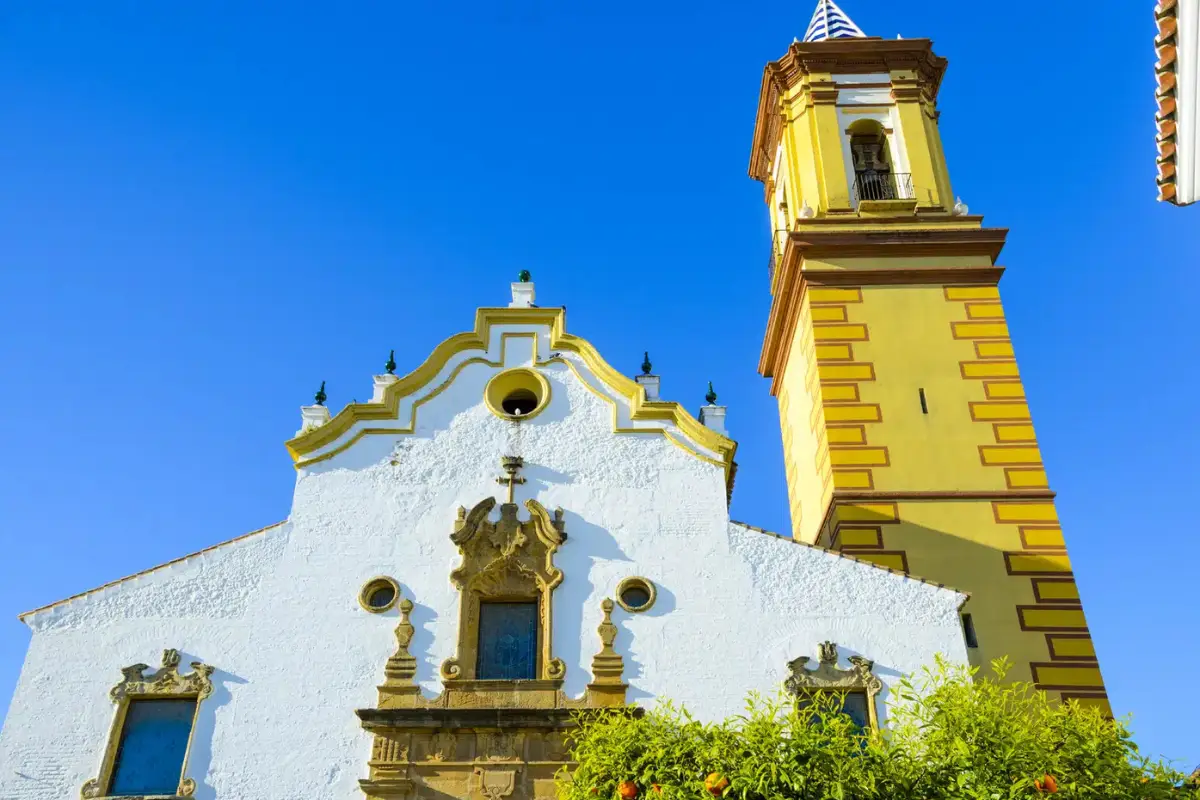 Tower of Parroquia Nuestra Señora de los Remedios church rising against a blue sky in Estepona