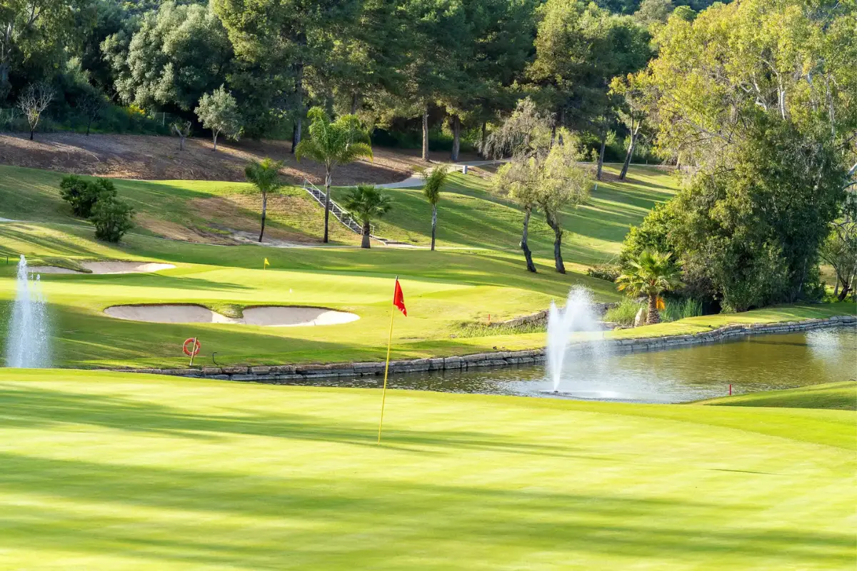 Green fairway with flag and water feature at an Estepona golf course