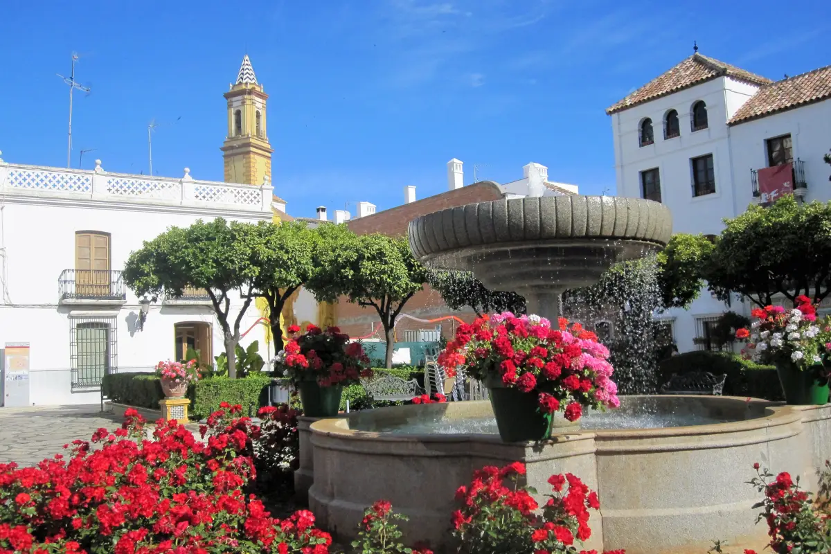 Flower-lined fountain in Plaza de las Flores, Estepona, with a church in the background