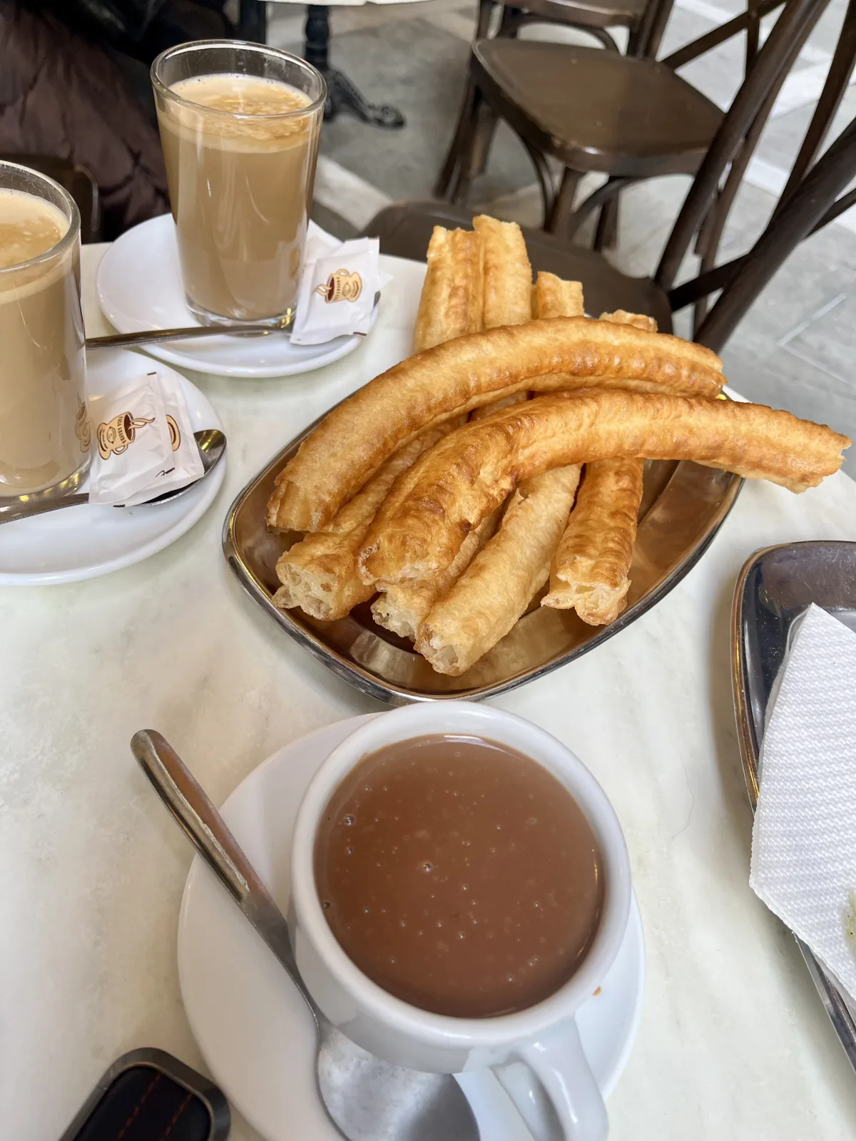 Churros and café con leche on a café table in Málaga
