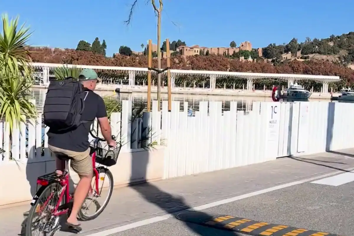 Man cycling along the Málaga seafront with the Alcazaba fortress in the background
