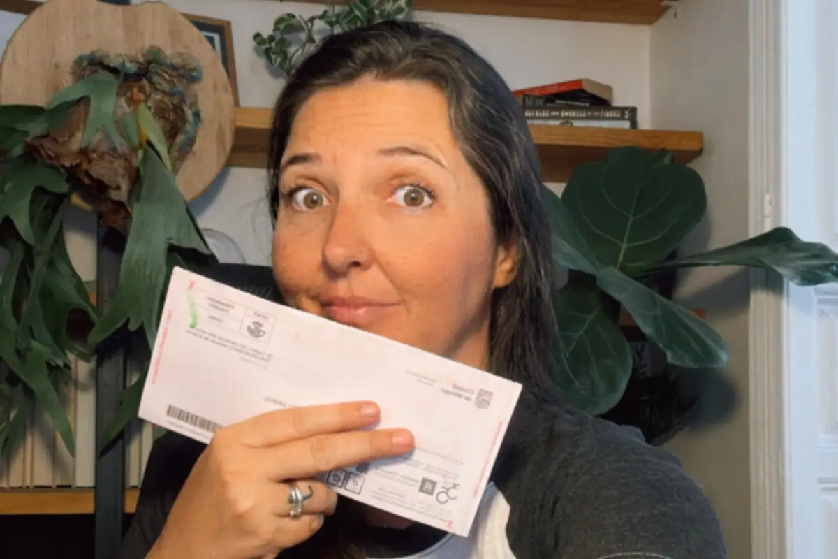 Woman holding up a Spanish driving fine with a surprised look on her face