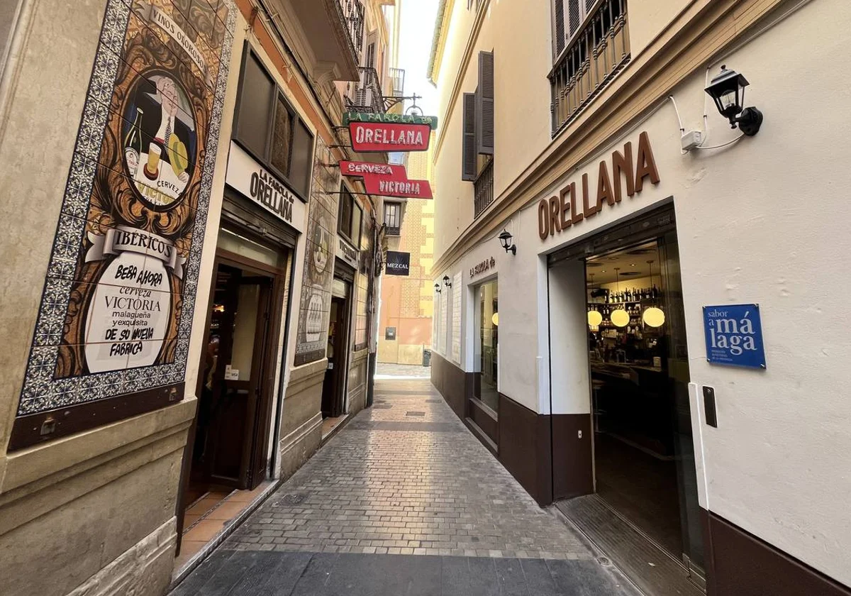 Narrow old town street lined with restaurant terraces in Málaga