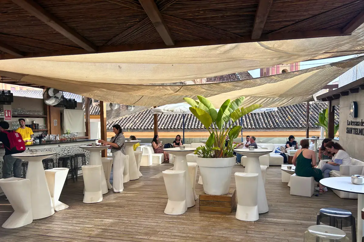 An open plan deck at San Telmo bar with tables, chairs and bar featuring a covered top and the author Heidi ordering a drink.