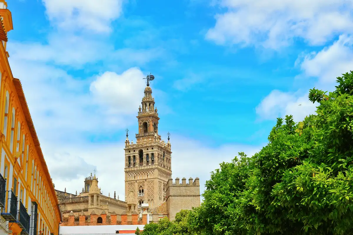 The Giralda bell tower of Seville Cathedral rising above orange trees and rooftops