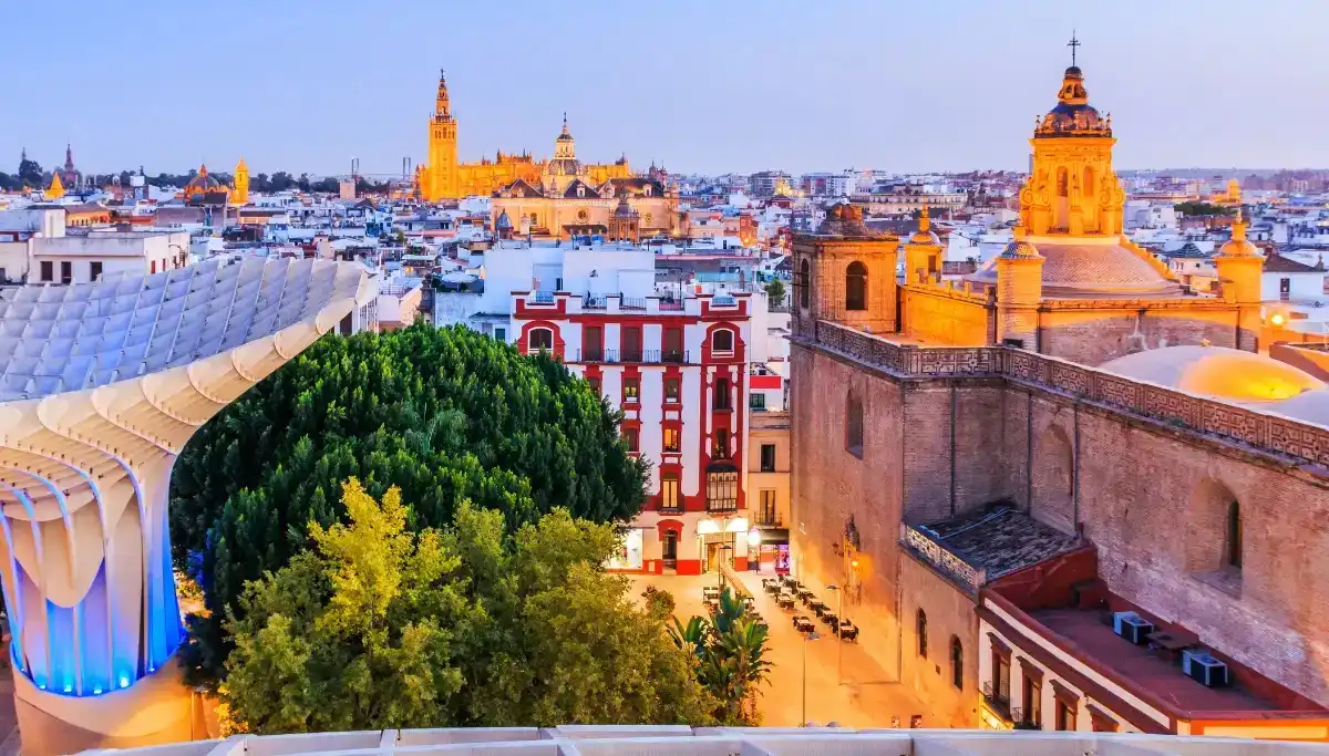 Seville skyline at dusk seen from a rooftop, with the Giralda tower lit up