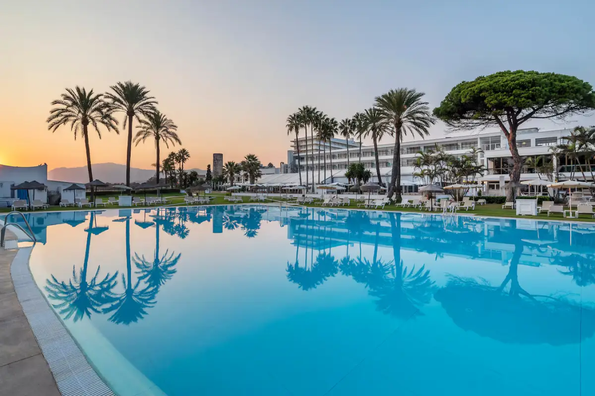 A large pool with cabanas on the side and apartments in the background at Sol Marbella Estepona Park.