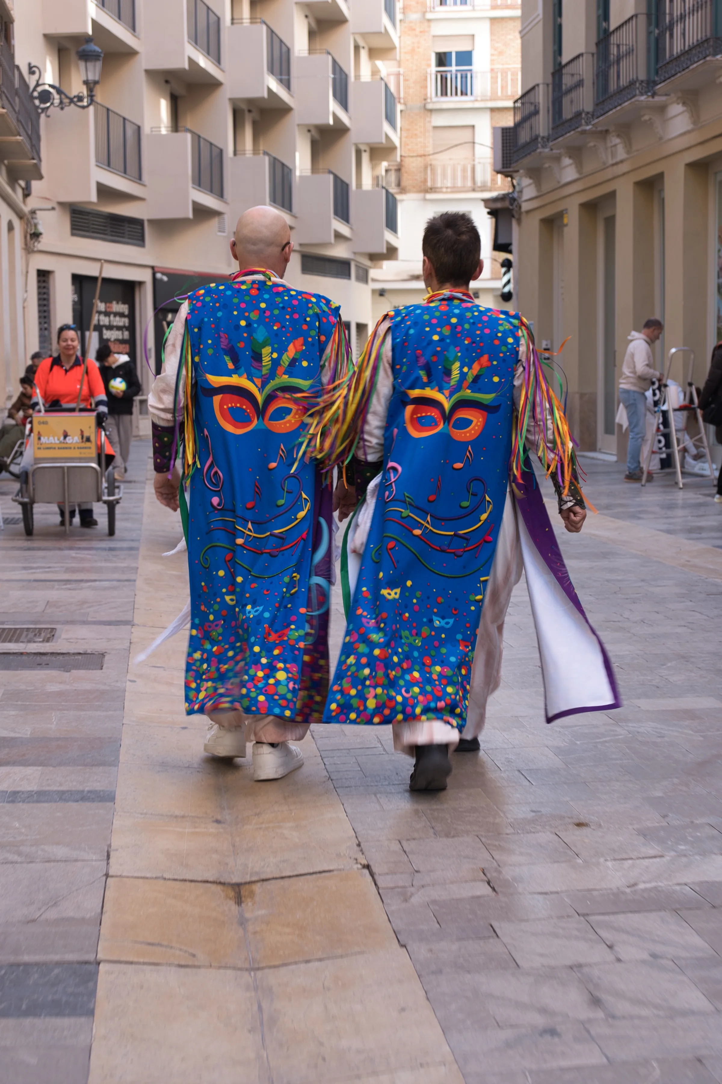 Two men in colordul blue costumes walking down a street.